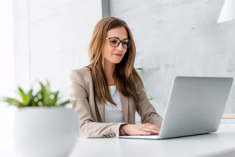 Geschäftsfrau sitzt am Schreibtisch mit den Händen auf der Tastatur des Laptops