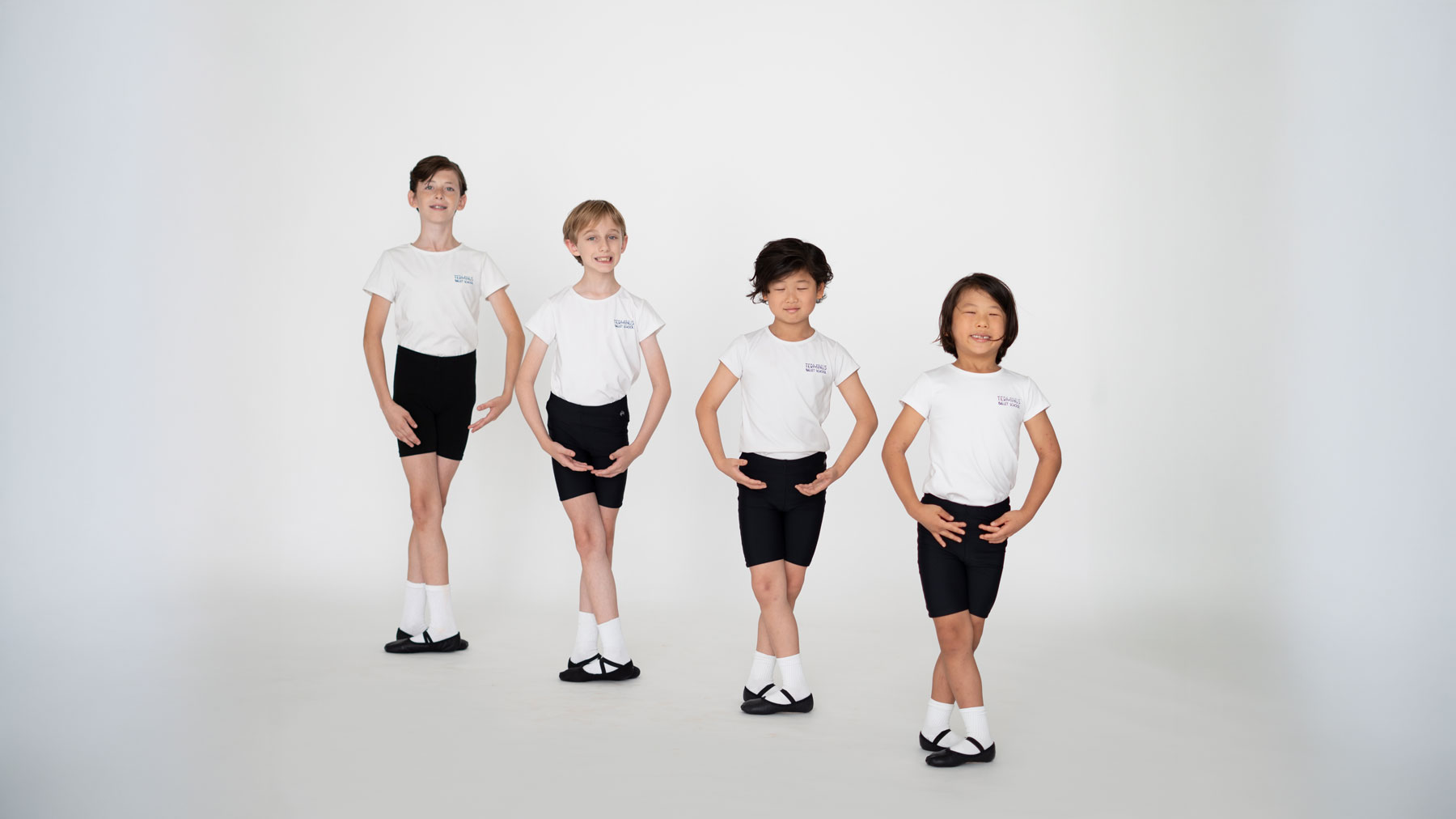 Young boys in ballet class posing in first position against a white background