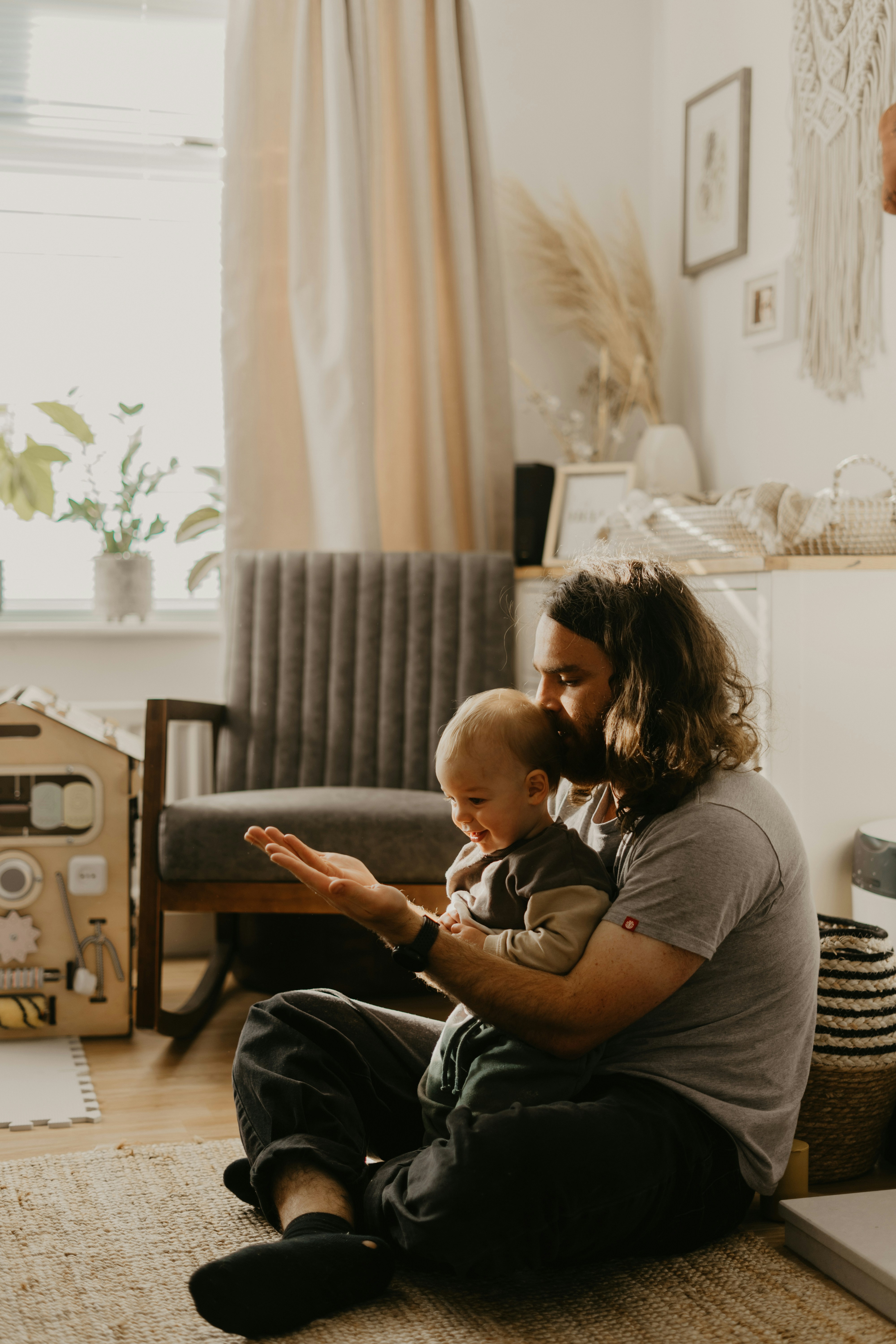 Parent sitting on the floor at home with a young child, representing family financial planning.