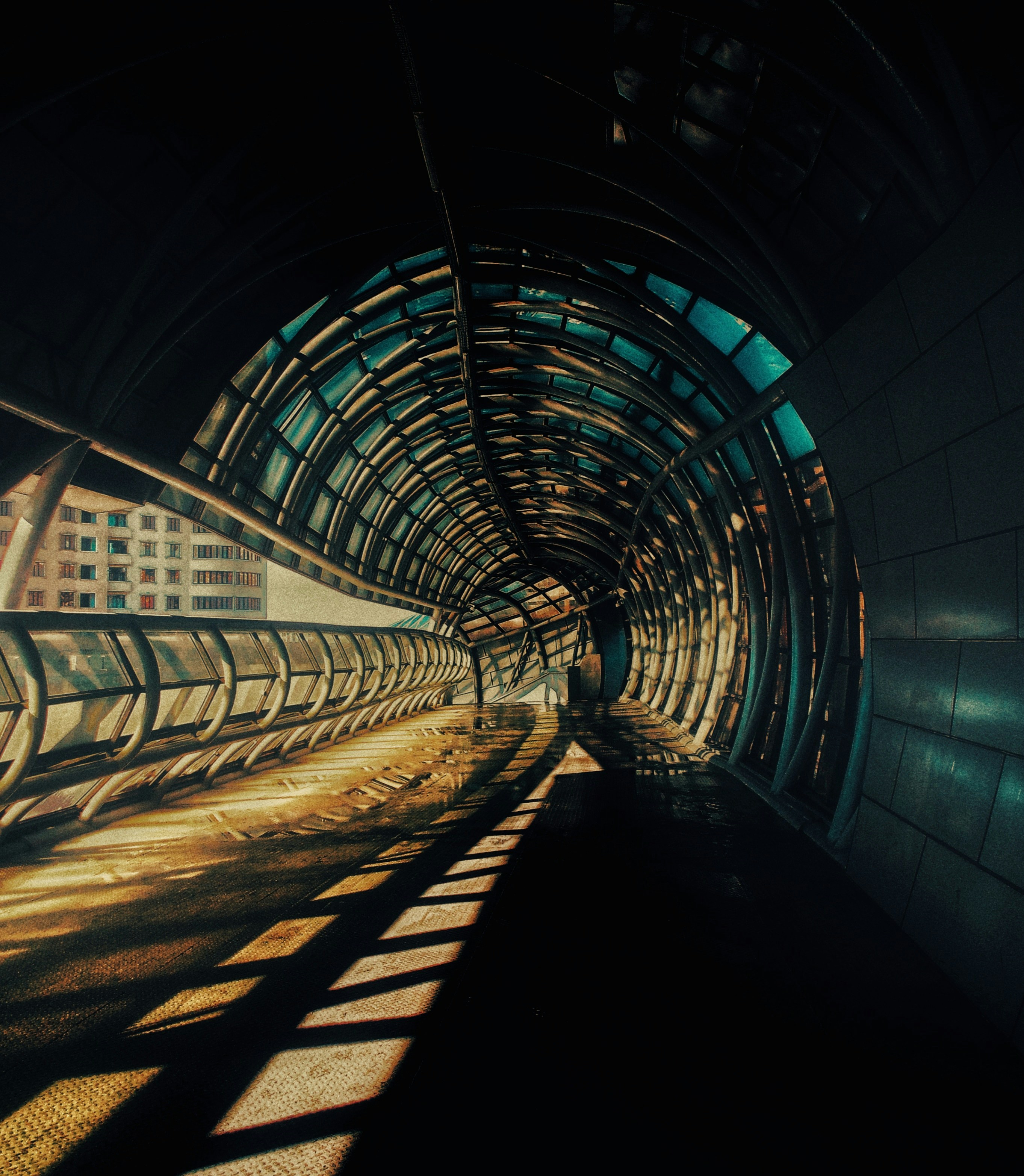 Sunlit tunnel walkway with geometric shadows, representing a path forward or financial journey.