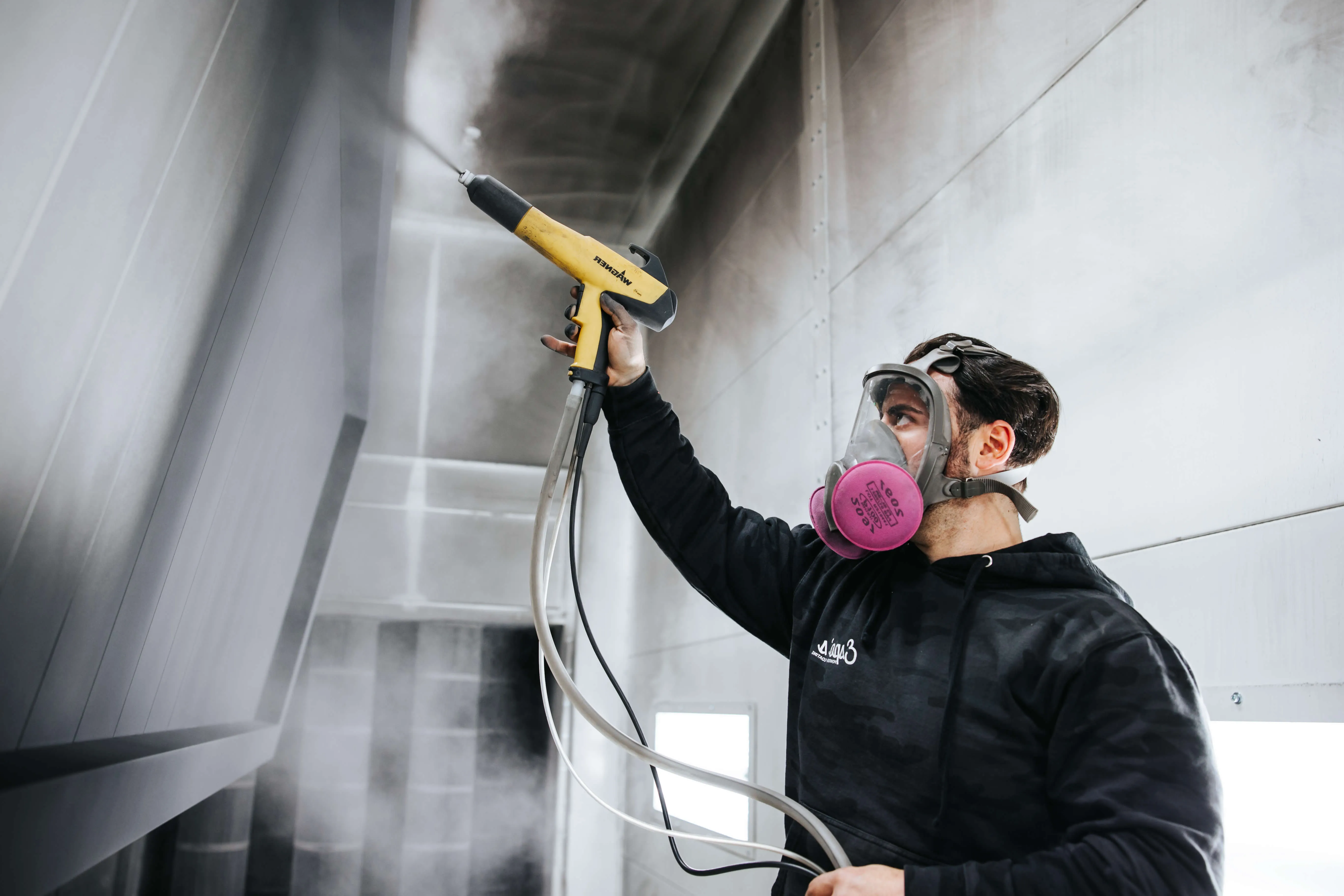 Espo's technician spraying powder coat in the booth, powder coating in New Jersey