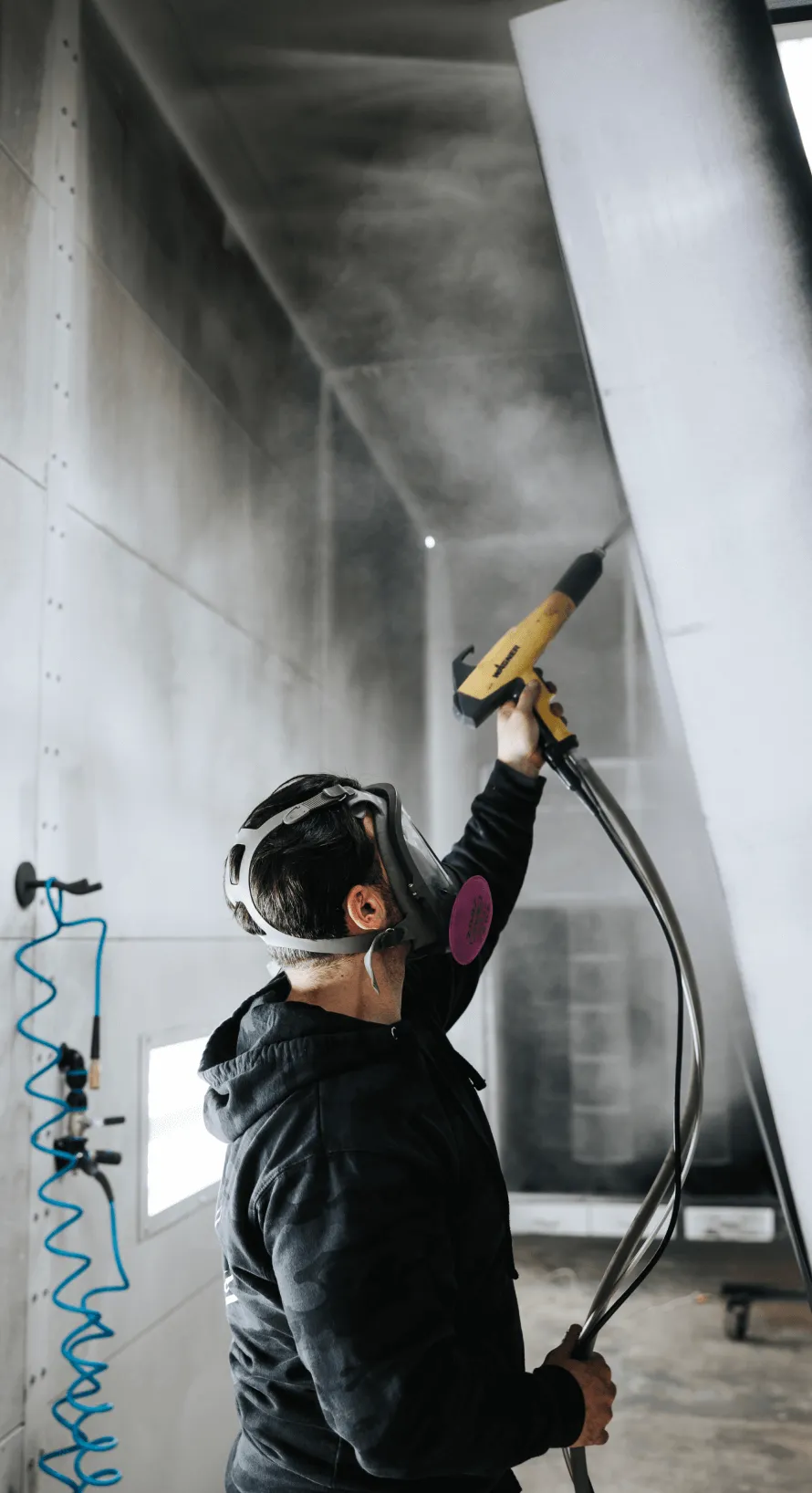 Technician spraying powder coat in the booth, showing powder coating instead of traditional paint