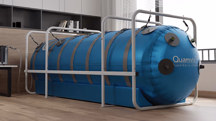 Blue Quamvis 320 hyperbaric chamber secured by metal frame inside a modern room with wooden floor and cabinets.