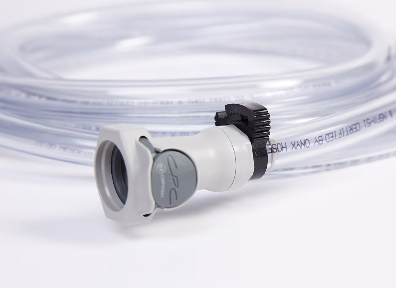 Gray and white hose connector attached to coiled transparent tubing.