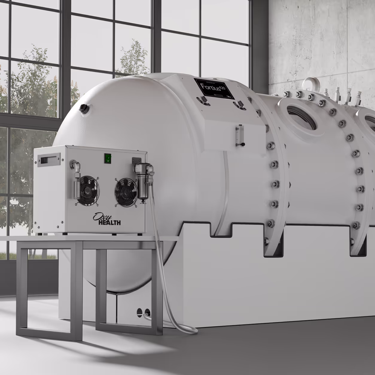 Large white hyperbaric oxygen therapy chamber with control unit on a metal stand in a room with large windows and trees outside.