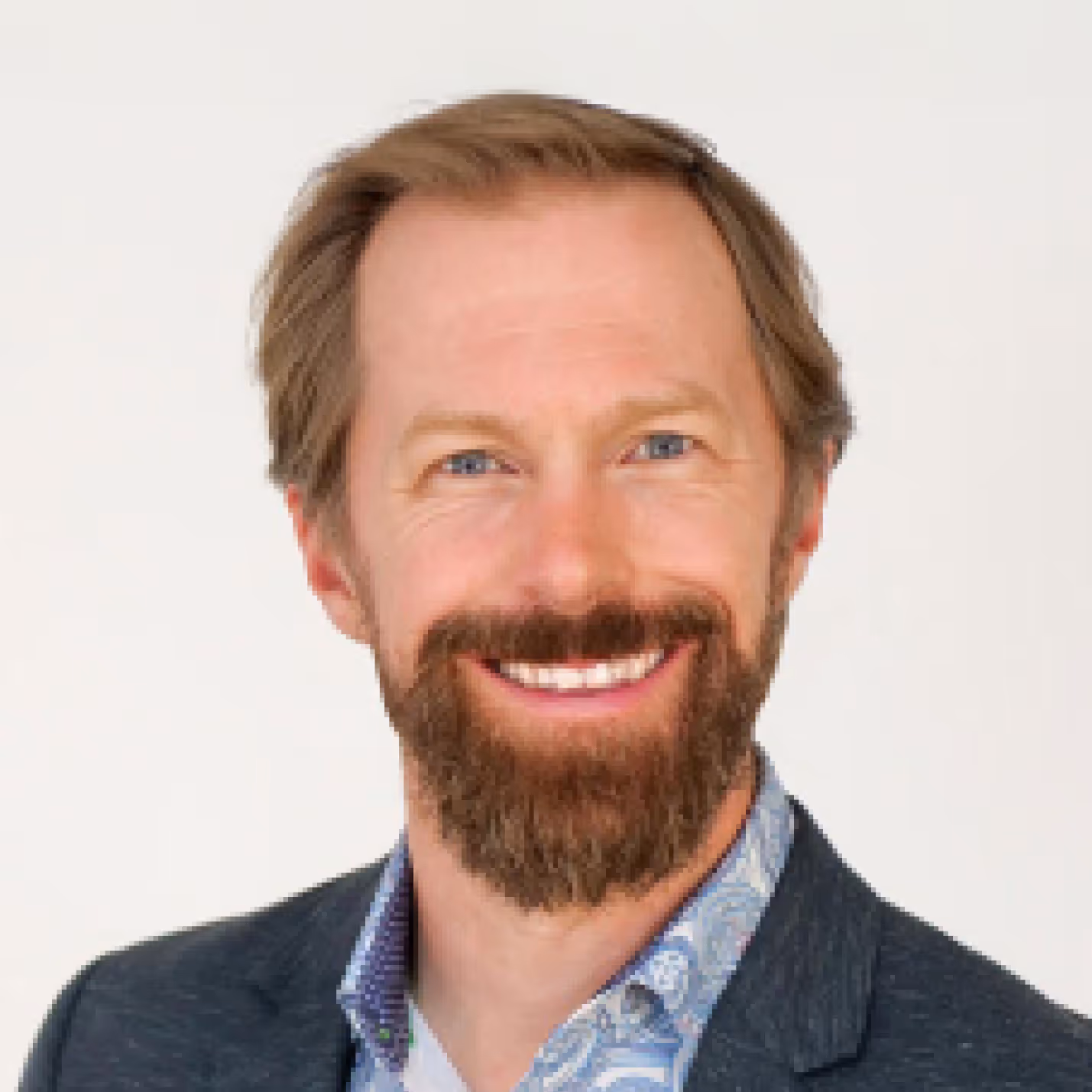 Dr. Moorcroft with light brown hair and beard wearing a dark blazer and a patterned shirt.