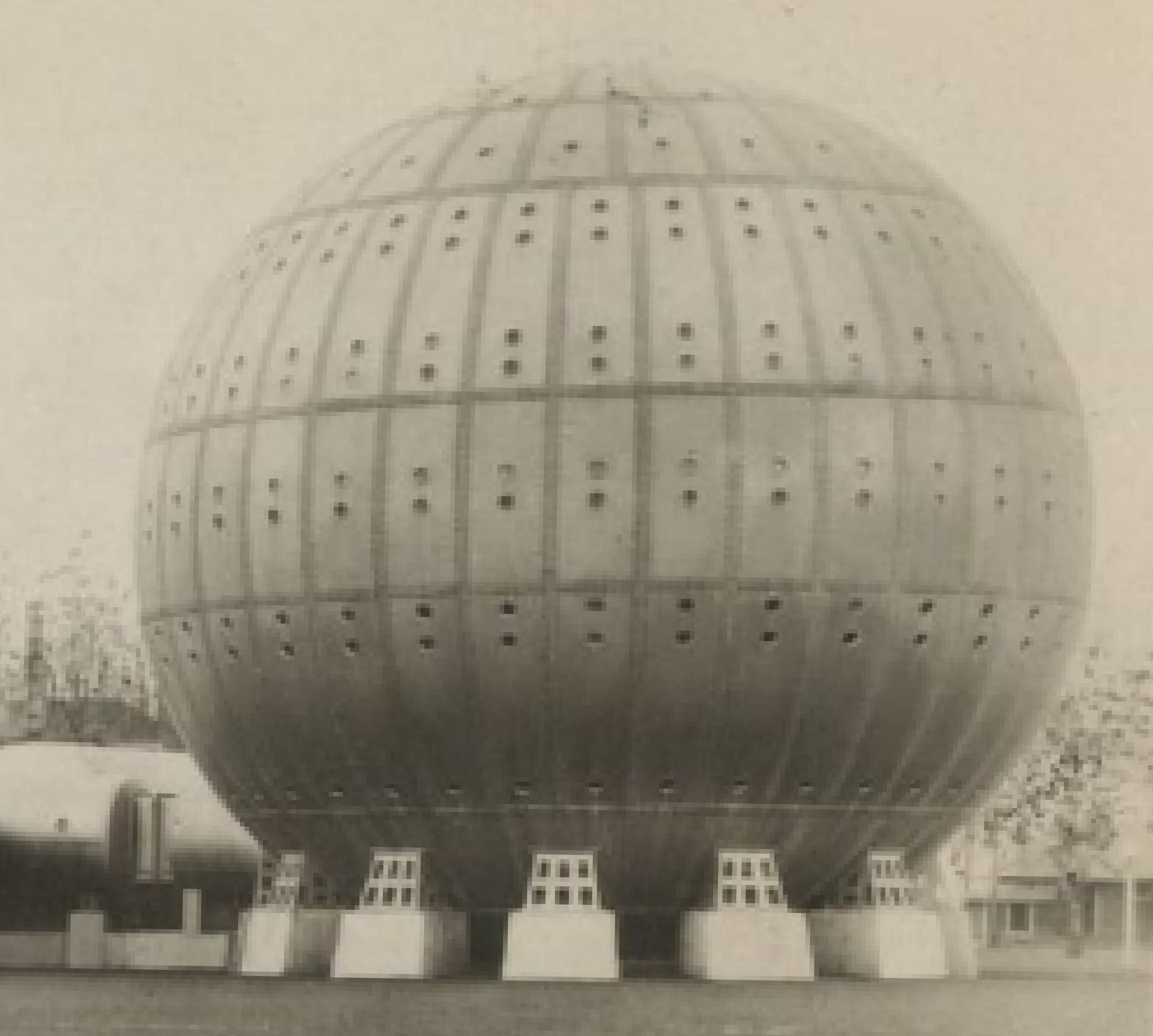 Historic black-and-white photo of a large metal hyperbaric spherical structure supported by concrete blocks with square openings.