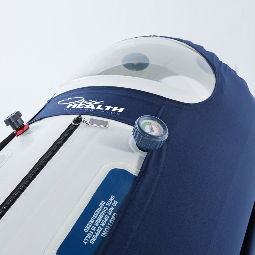 Close-up of a white and blue hyperbaric oxygen chamber with pressure gauge and zipper.