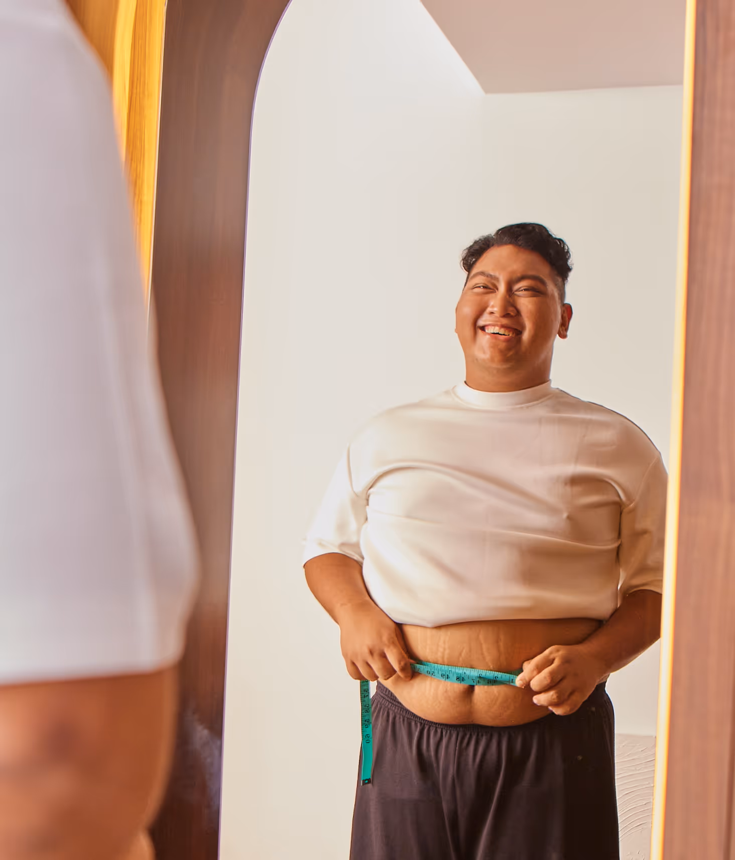Singaporean man in a dark hoodie, using his phone while sitting down with his leg against the edge of a table