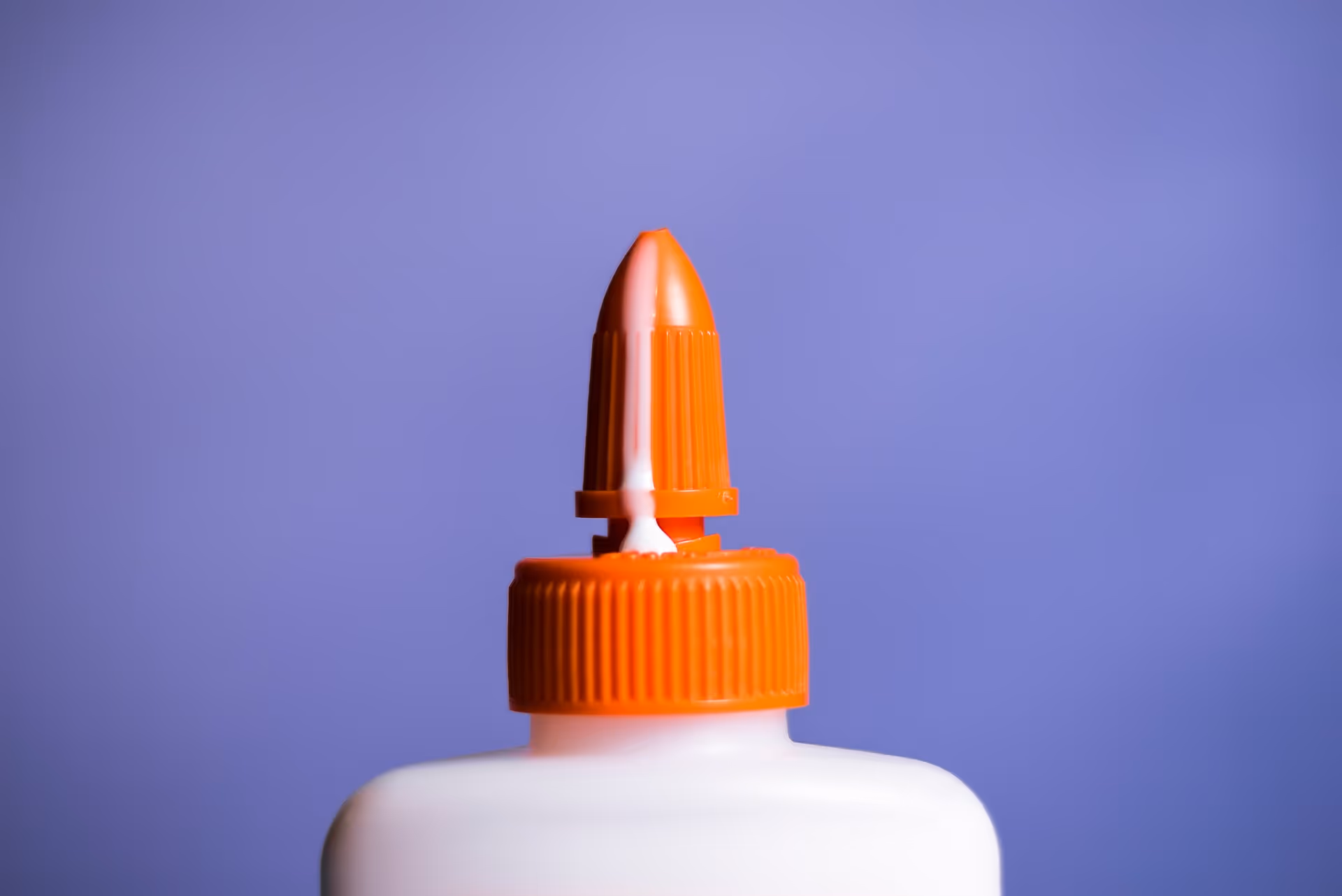 White glue overflowing from the tip of its container