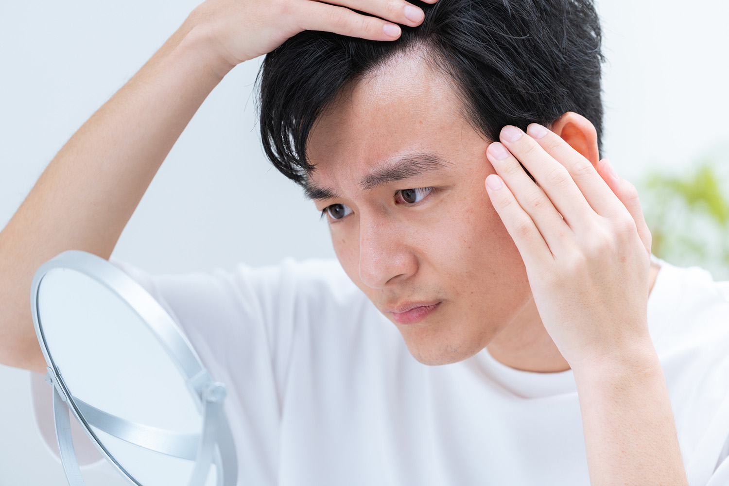 一名男士正憂慮地檢查自己的髮線狀態