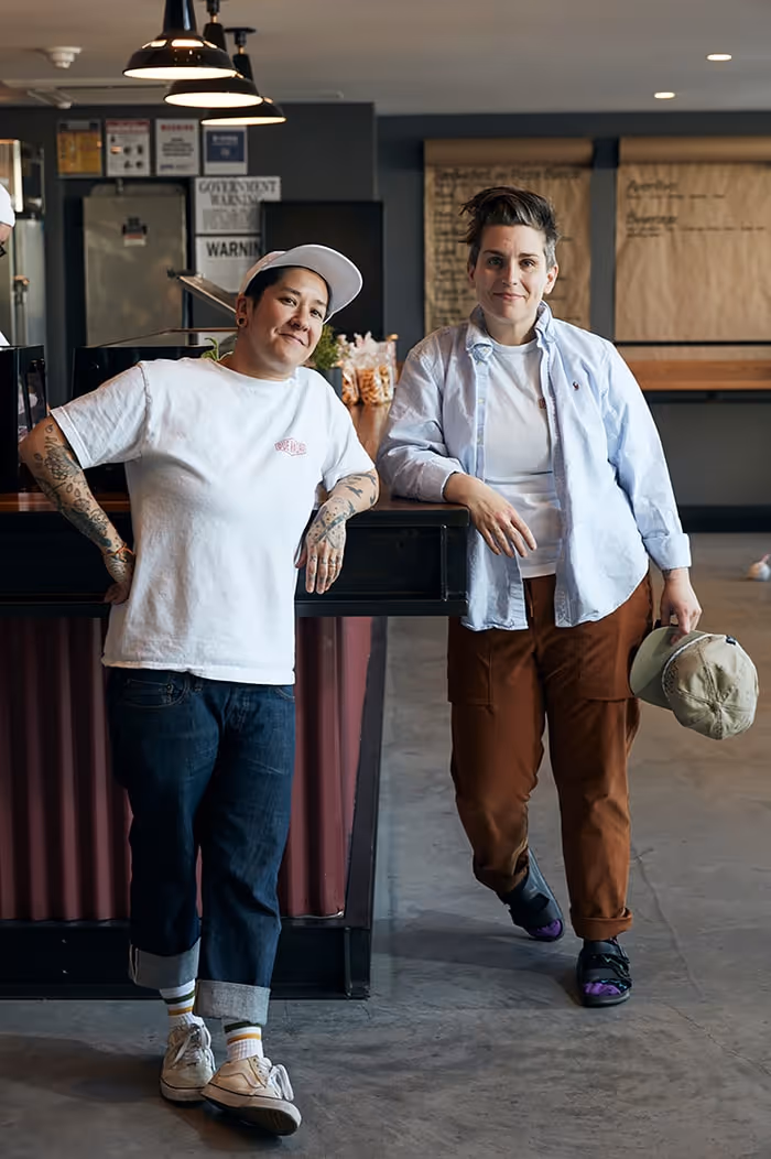 Photo of Erika and Jocelyn, owners of Due Madri, leaning on the restaurant counter