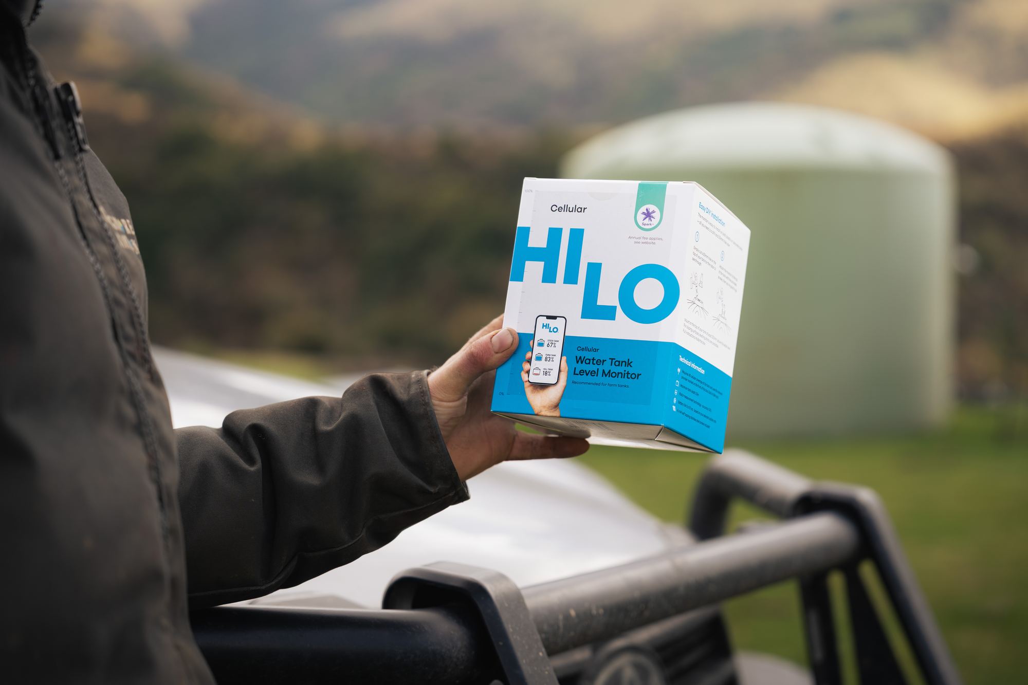 HiLo water tank monitor box held in front of a farm water tank
