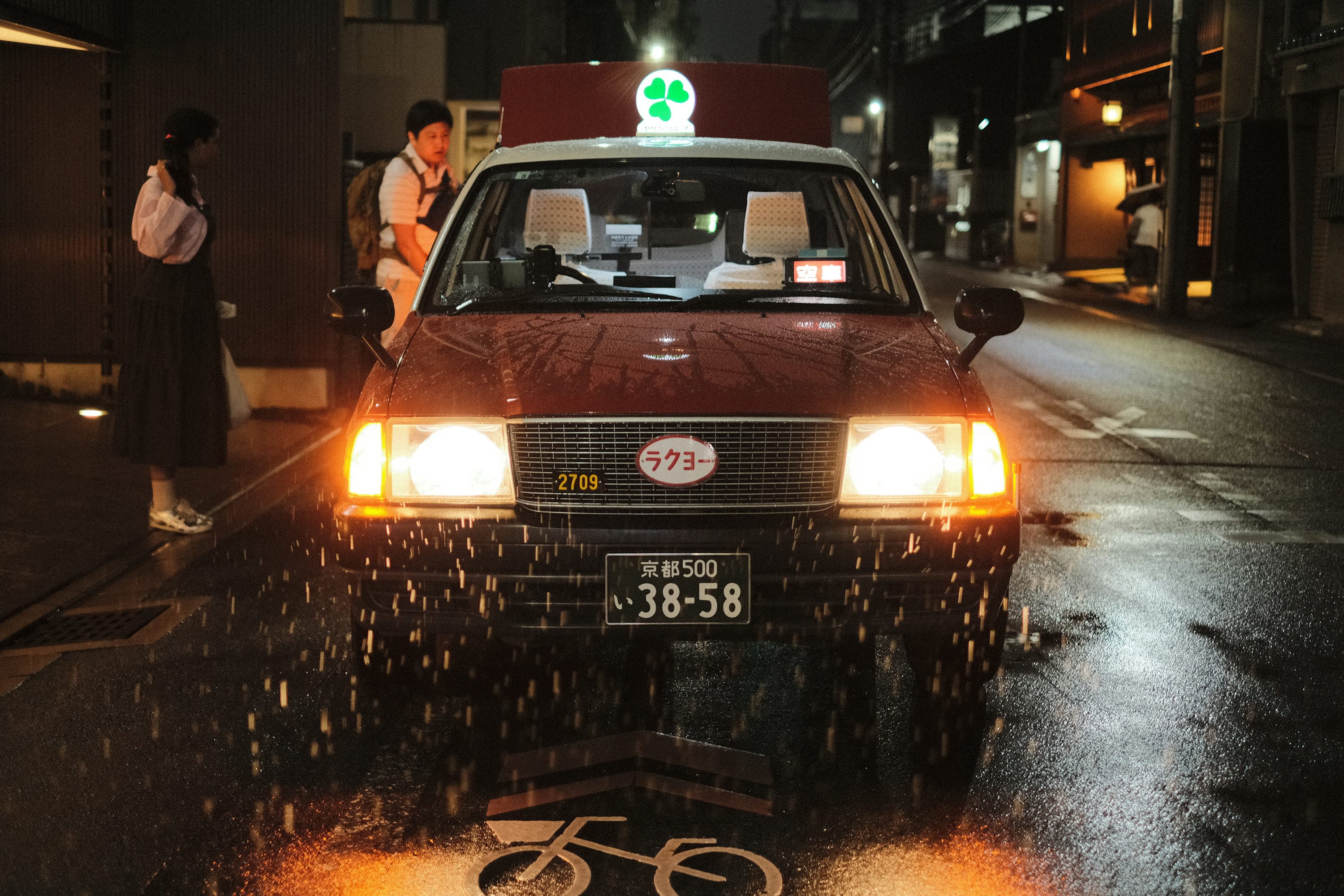 A car driving down a rain soaked street at night