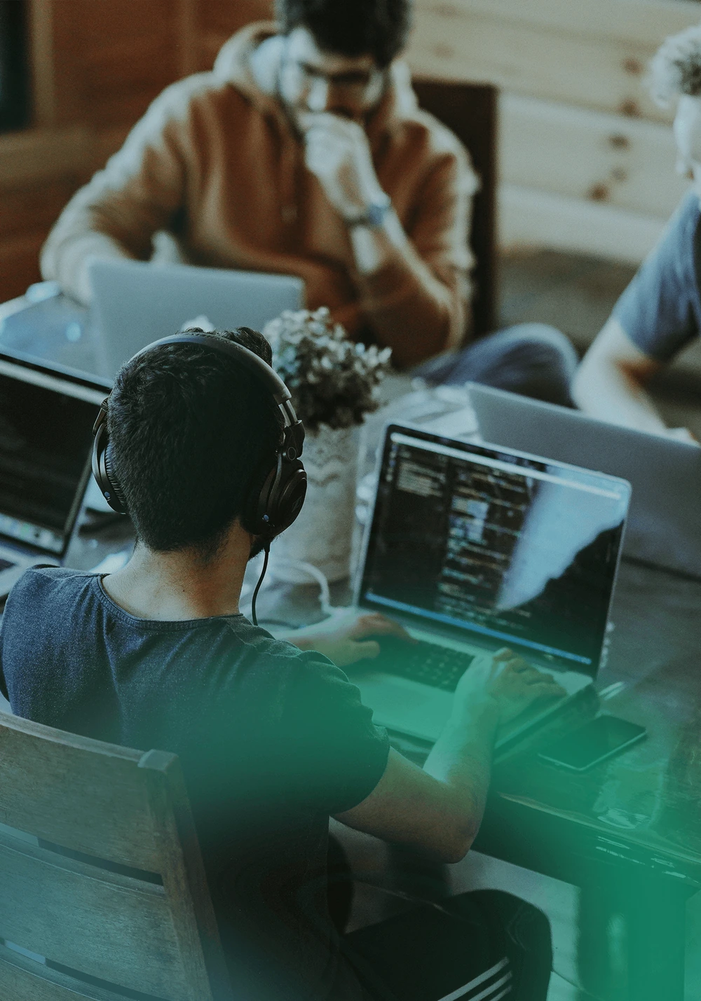 A group of people collaborating while working on laptops, with code visible on the screens.