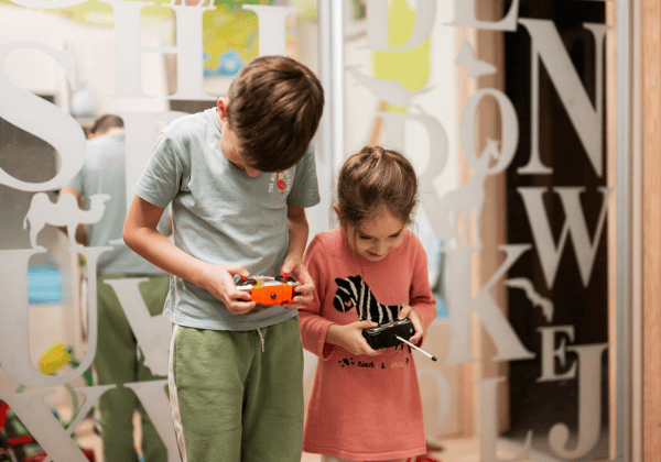 Boy and girl playing with remote control in children's room