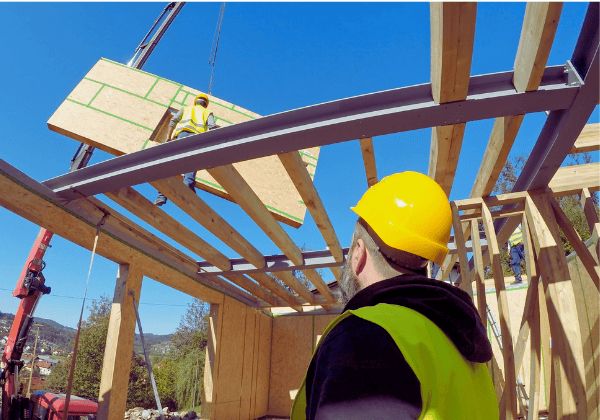 Construction worker looking at crane loading construction frame at construction site