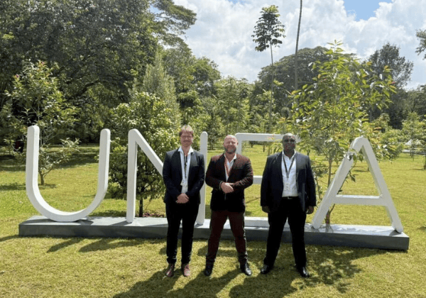 Adam Stingemore poses with another two men in front of the UNEA sign