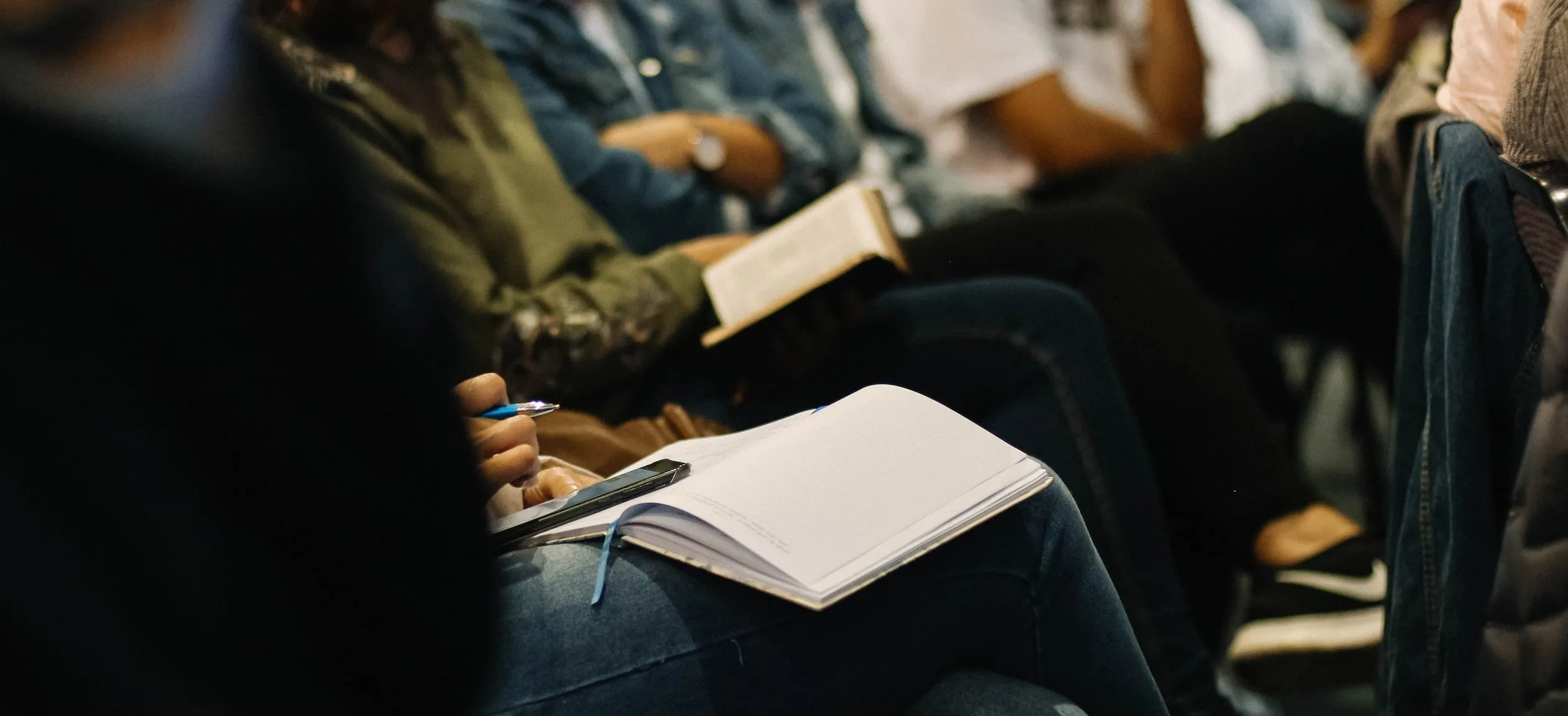 A close up of journals and bibles on people's' laps.
