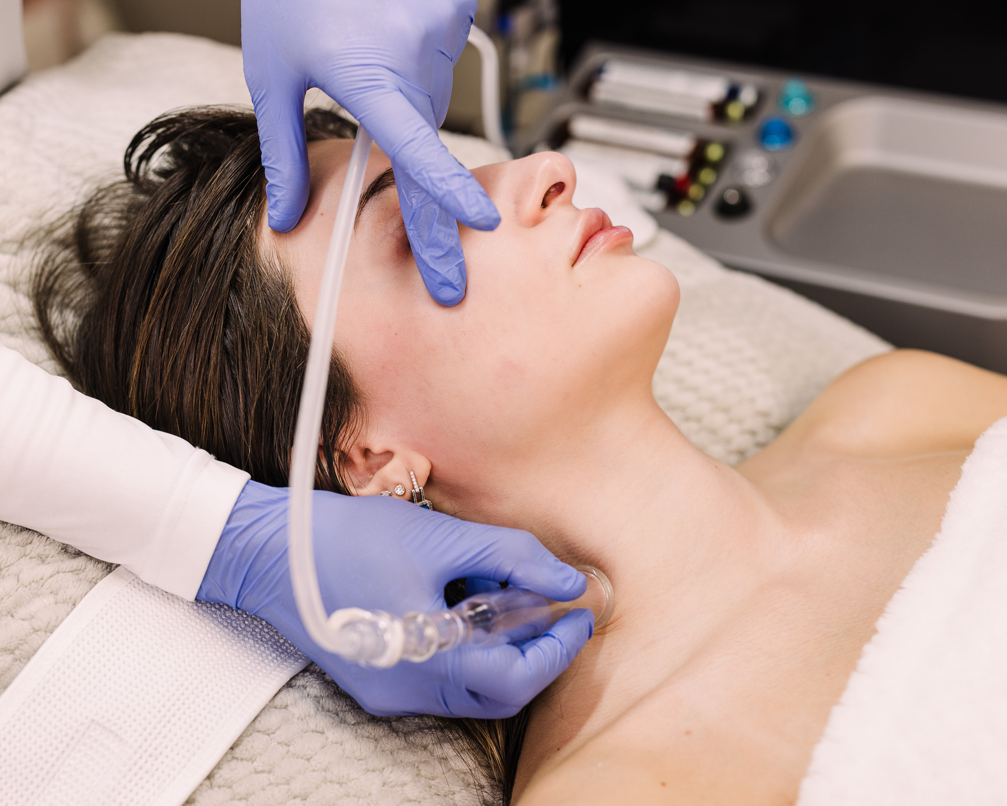 A woman receives a lymphatic drainage facial using a HydraFacial tool at a Boston spa, helping reduce puffiness and boost circulation.
