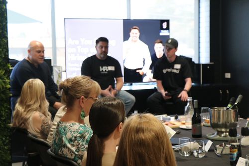 Business event with panel discussion on hiring; attendees at tables.