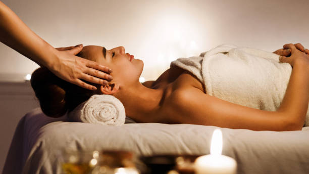 Young woman enjoying face massage in spa salon Young woman enjoying face massage with aromatic candles in spa salon massage services stock pictures, royalty-free photos & images
