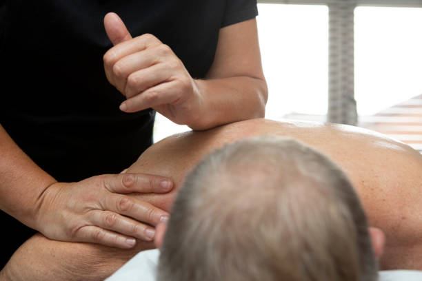 Female hands and arms giving a deep tissue massage to a man lying face down Man receiving a deep tissue massage by a female masseur in a therapy room at home deep tissue massage stock pictures, royalty-free photos & images