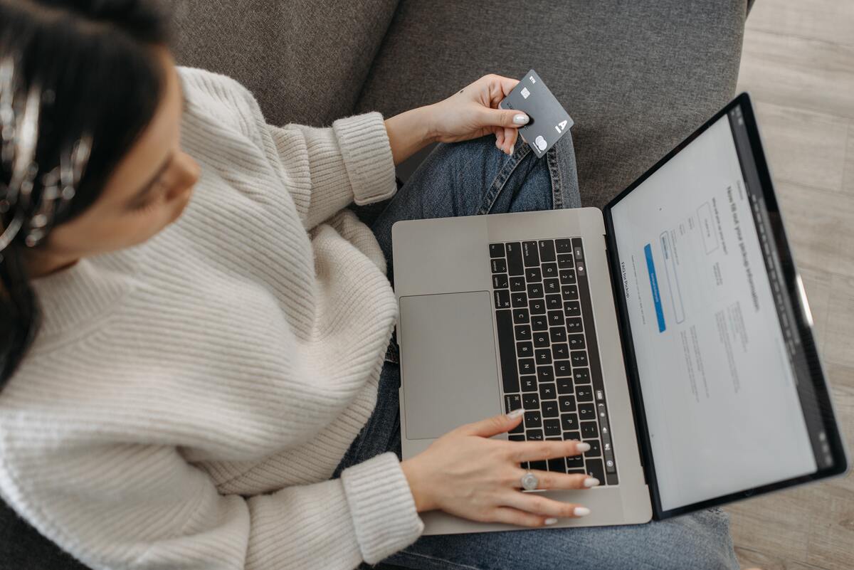 person-using-PC-with-credit-card-in-other-hand