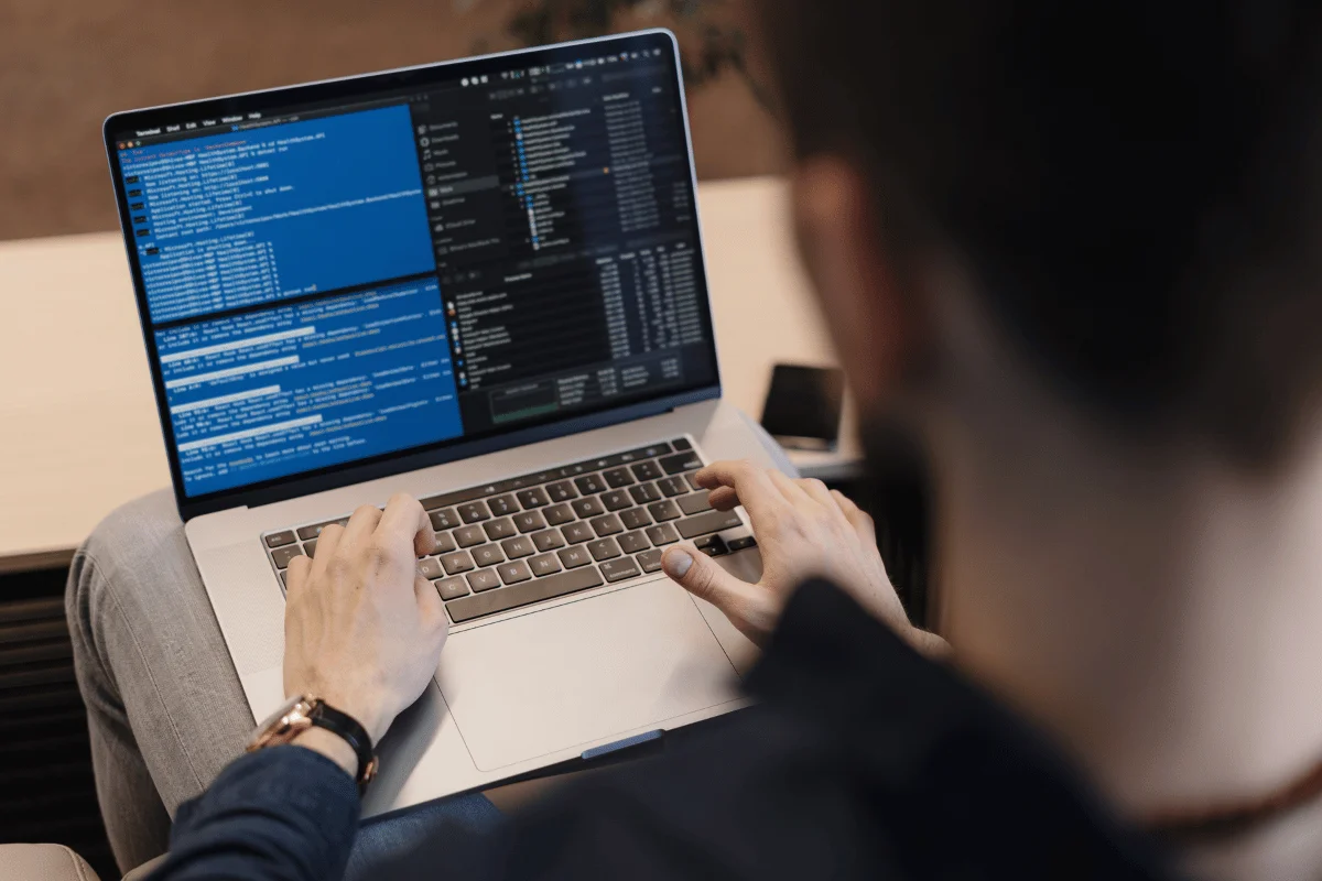 Developer coding on a laptop with terminal and code editor open.