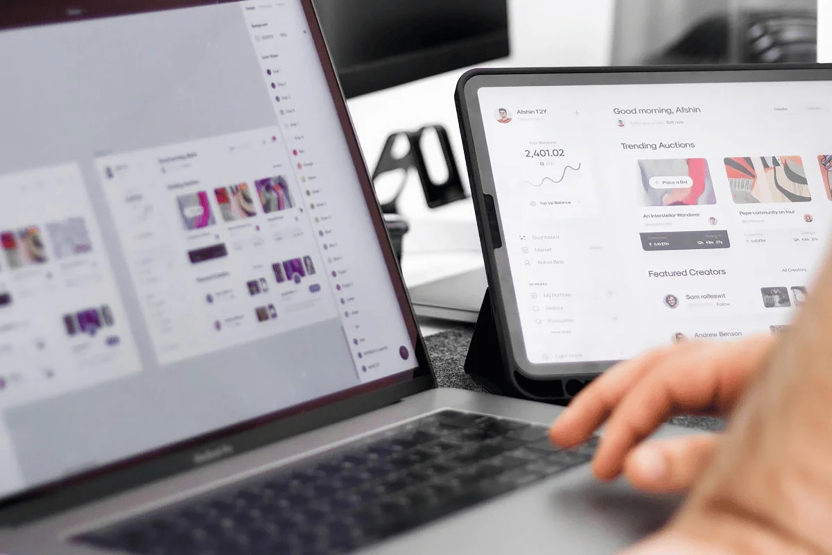 A laptop and tablet showing different user interfaces on digital platforms.