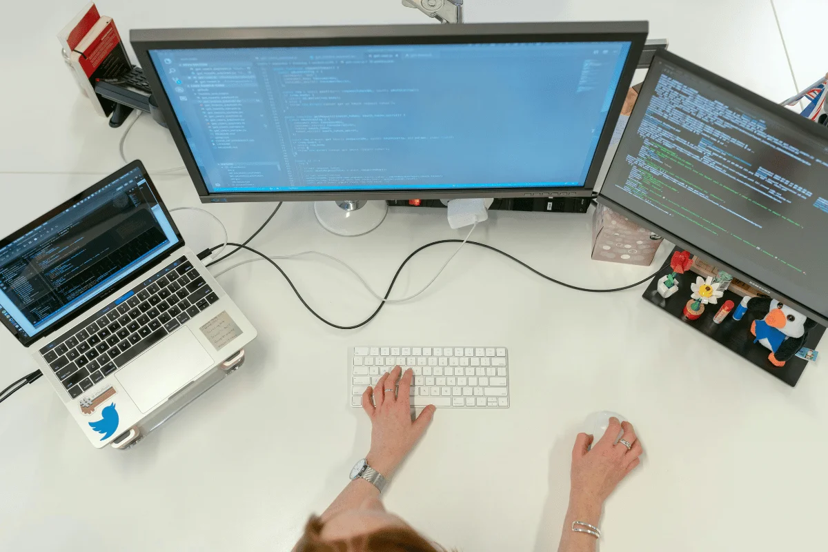 Overhead view of a programmer working on triple monitors.