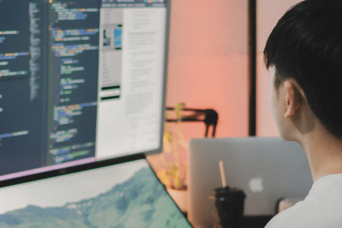 Developer looking at computer monitor with code editor open.