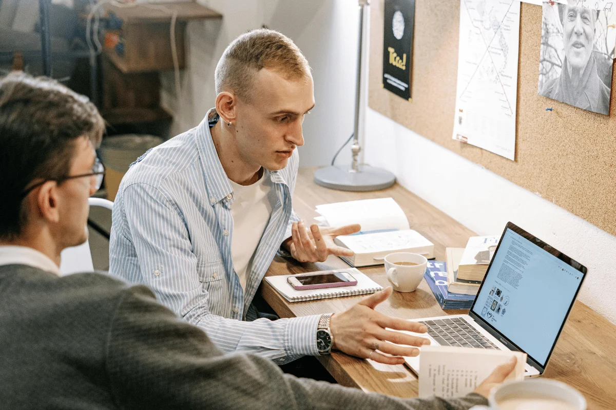 Two colleagues discussing work while looking at laptop screen.