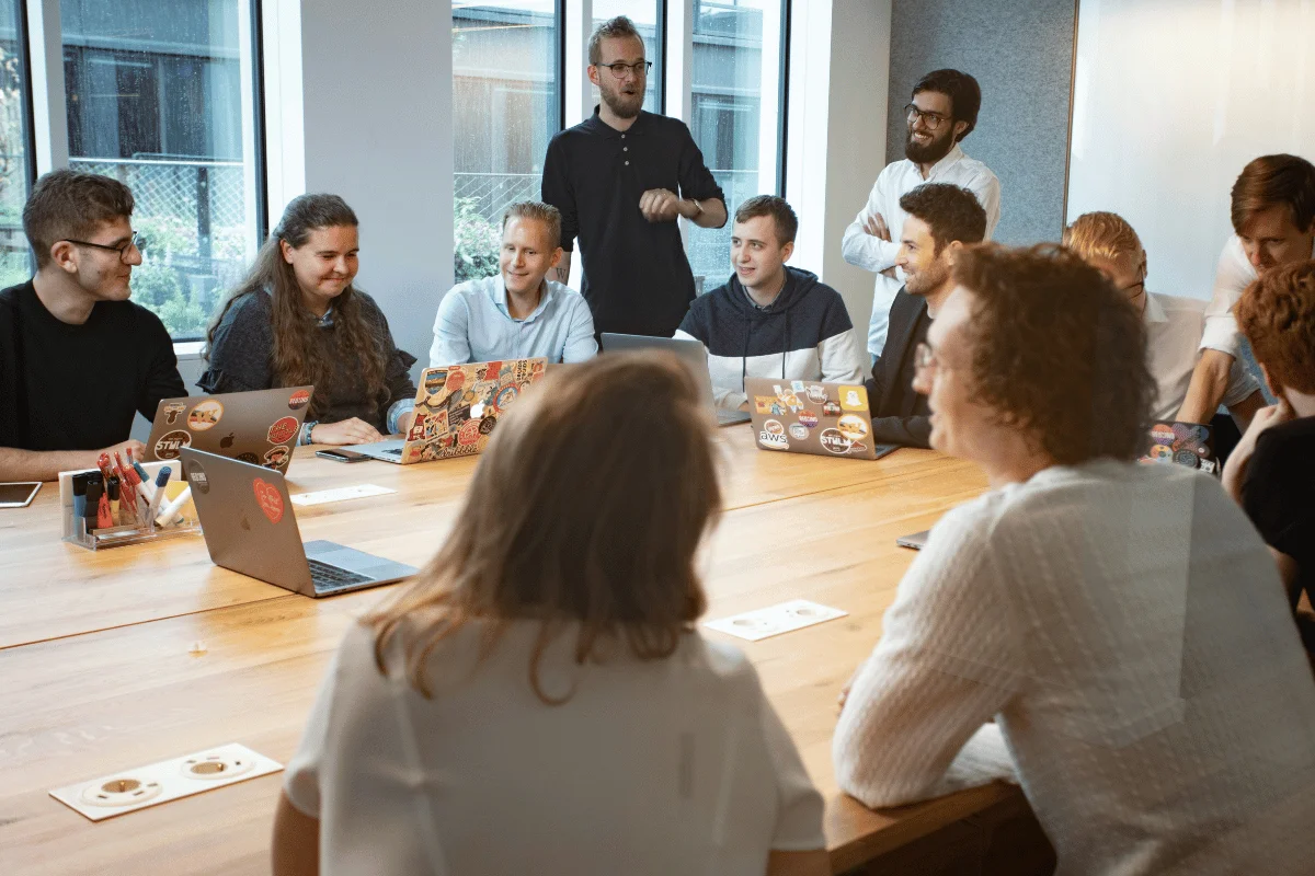 Startup team gathered in meeting room with laptops.