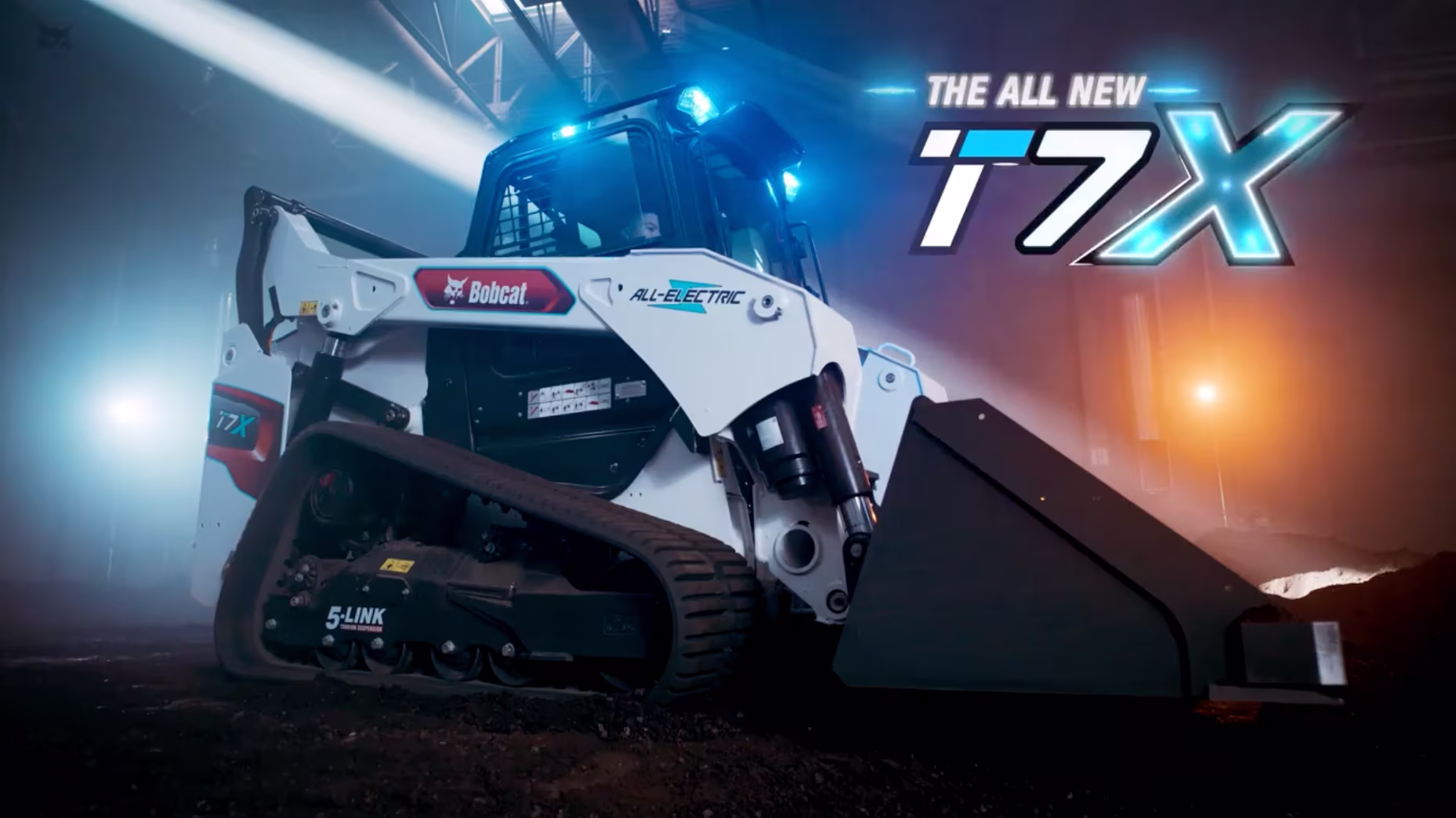 A sleek, all-electric Bobcat T7X loader is showcased in a dimly lit, industrial setting with blue and orange lights, highlighting its modern design.