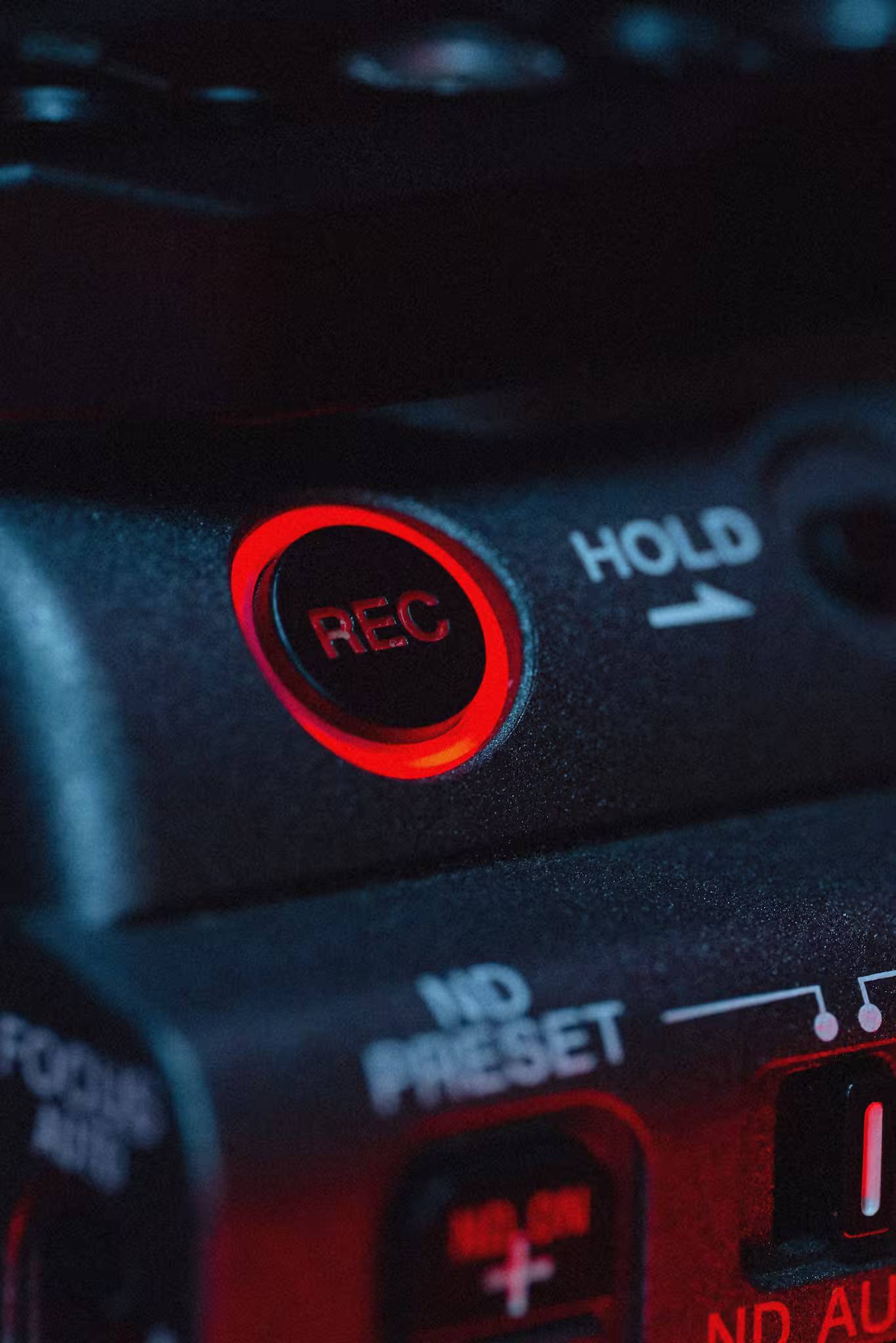 Close-up of a camera's red illuminated REC button and nearby controls labeled HOLD and ND PRESET.