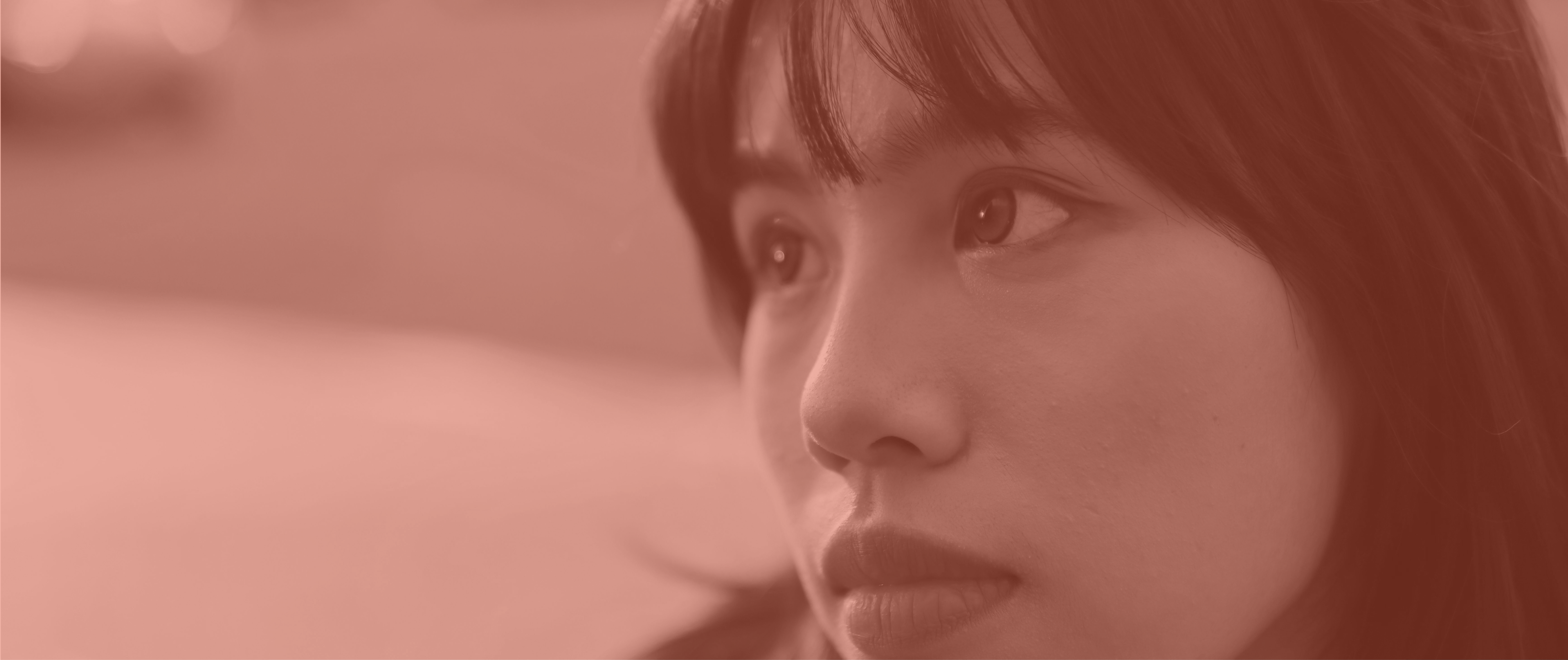 Close-up of a young woman looking thoughtfully to the side with soft warm lighting.