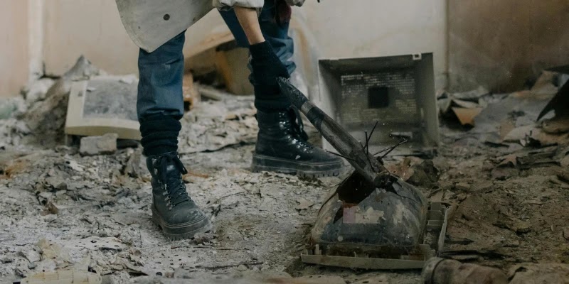 Woman in army boots smashes a tv with a bat in a smash room in Melbourne