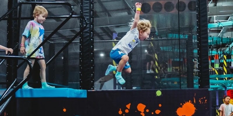 Two young boys leap off an obstacle course in Area 51