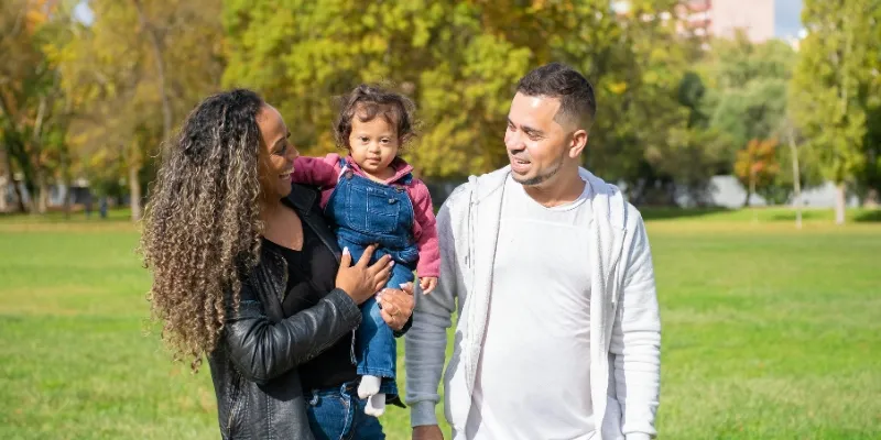 Family walking together in a green park on a sunny day.