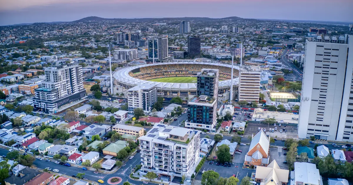 Gabba stadium at dusk with lit field and sunset sky