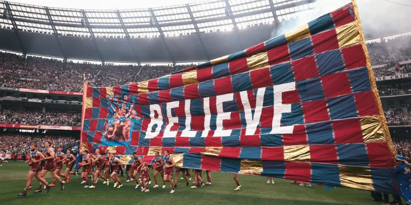 Brisbane Lions team holding up banner on Gabba ground