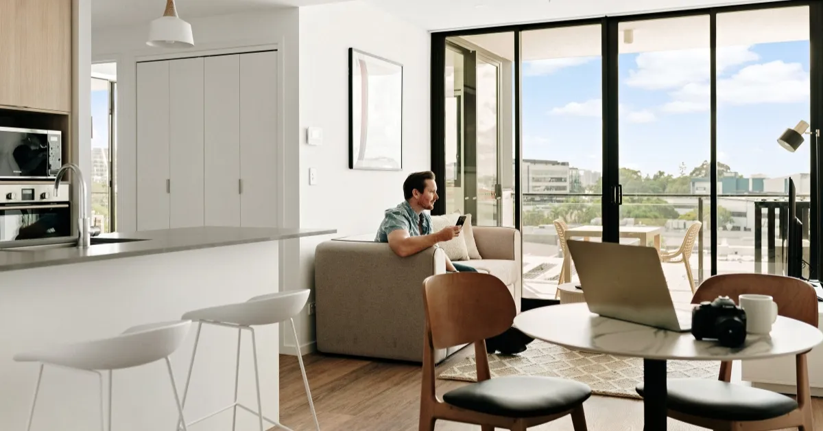Man relaxes in serviced apartment open plan living space