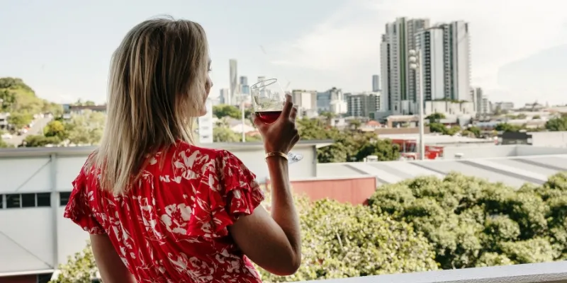 Guest relaxing on a private balcony at Rambla serviced apartments overlooking Brisbane city skyline.