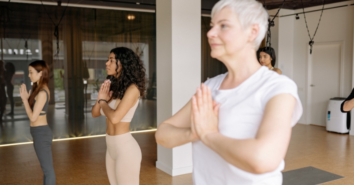 Group of women in yoga class with hands in prayer position.