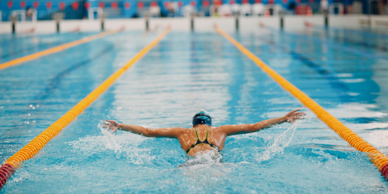 Swimmer doing butterfly stroke in pool.