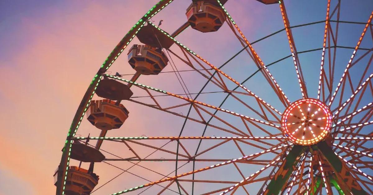 Ferris wheel at dusk, illuminated with string lights.