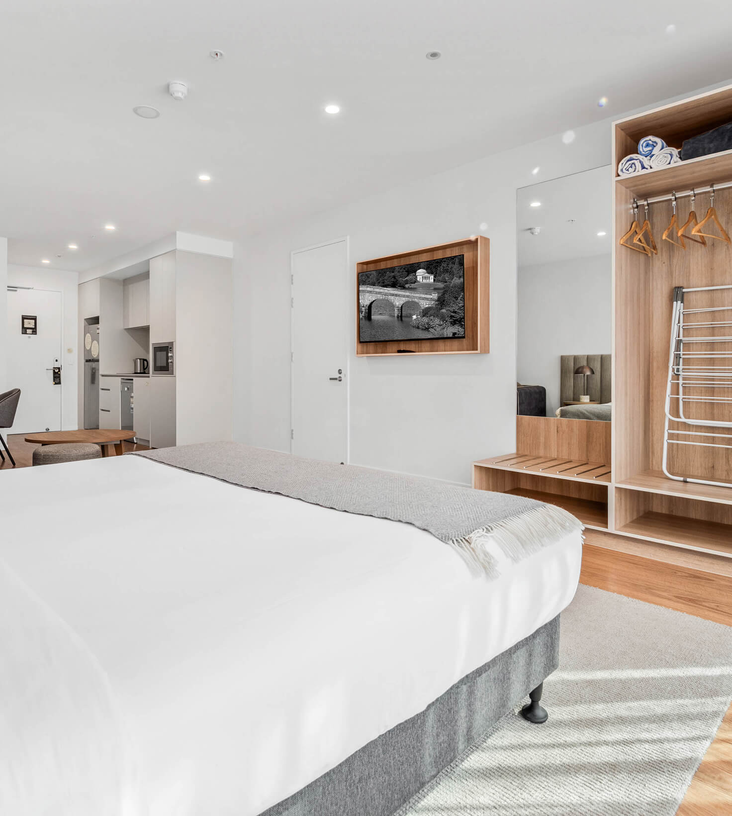 King bed looking through to the kitchenette and open robe in a Deluxe Studio Apartment at Rambla @ Story House