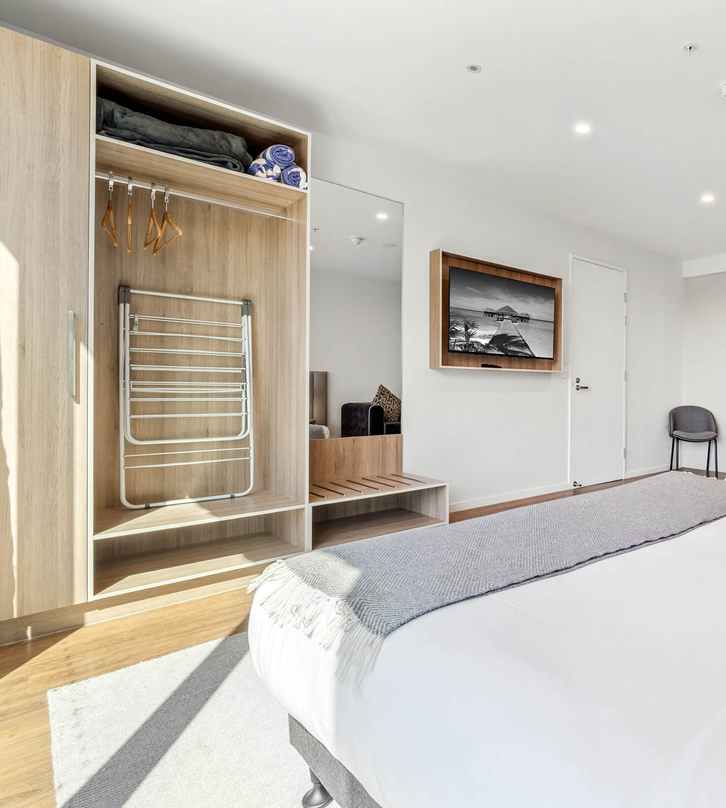Open robe with hanging space and drying rack opposite the wall-mounted TV in a Deluxe Studio Apartment at Rambla @ Story House