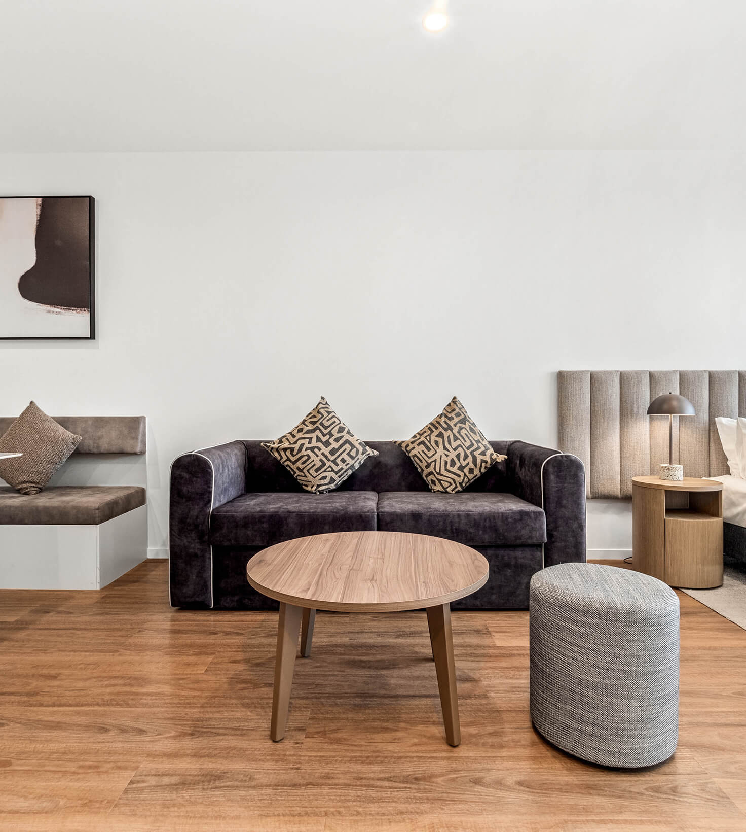 Sofa and round coffee table between the dining banquette and the bed in a Deluxe Studio Apartment at Rambla @ Story House
